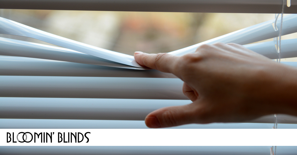 hand pushing blinds down to see out of the window