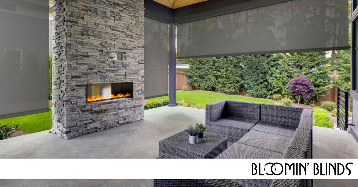 Large outdoor space with fireplace and couch surrounded by exterior shades.